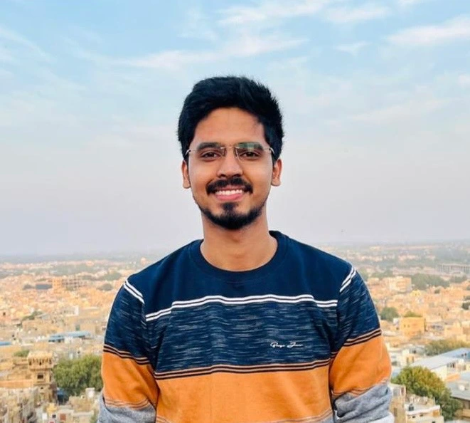 Manak Upadhyay, smiling, on a rooftop above a city